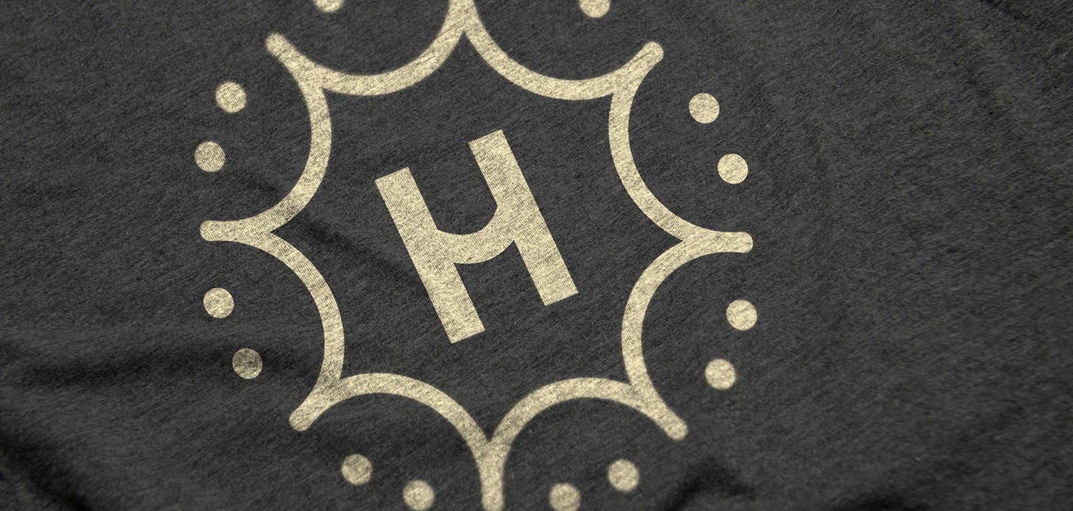 Close up of screen printed Happie logo on dark gray T-Shirt